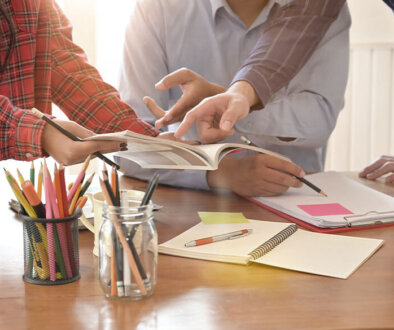 Work team looking and pointing to an open book.
